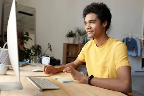 boy in yellow t-shirt using a imac